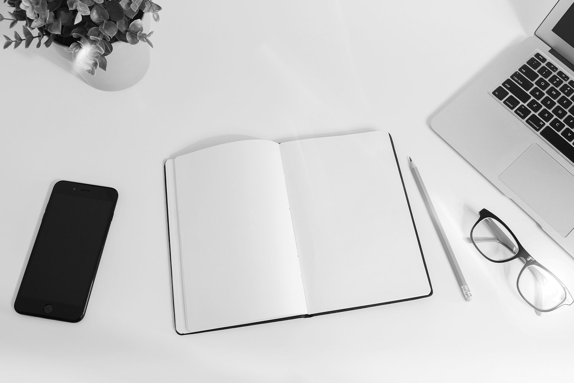 A tidy desk with notebook, phone and laptop